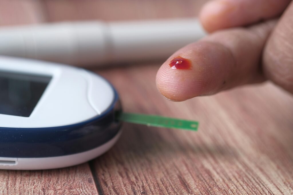 A close-up of a finger prick and blood glucose monitor for diabetes testing.