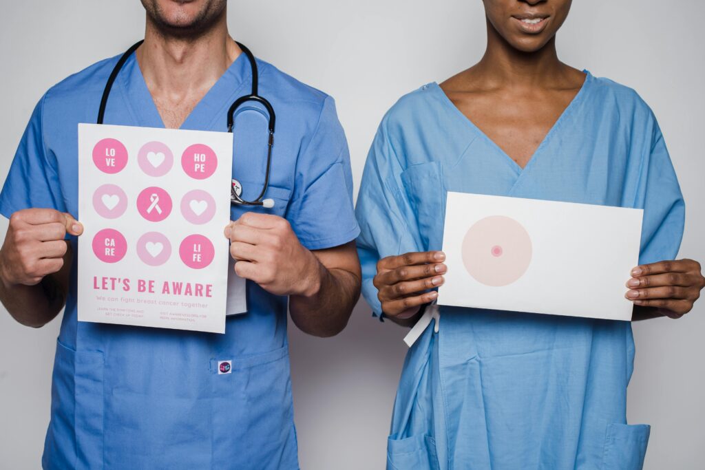 Two healthcare workers holding breast cancer awareness posters promoting early detection and education.