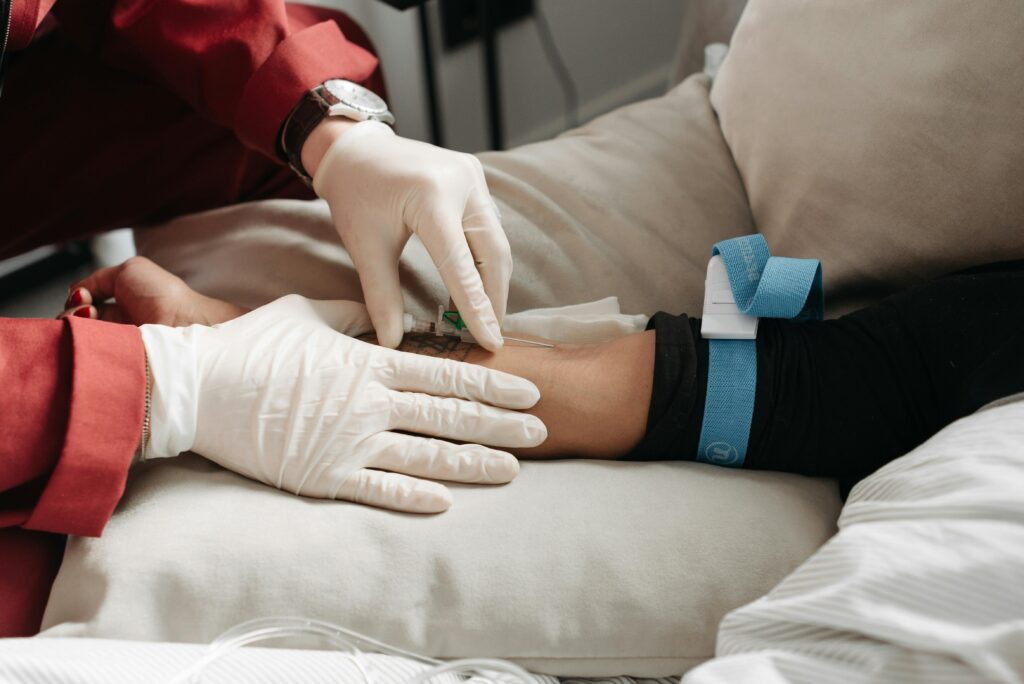 Medical professional in gloves inserting intravenous line into patient's arm in clinic setting.